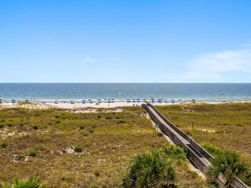 a beach with a wooden fence and the ocean at Tidewater Orange Beach #202 in Orange Beach