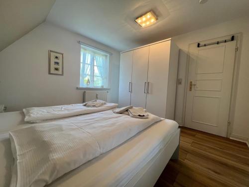 a white bedroom with a large bed and a window at Wohnen auf'm Lande HT 6 in Oldsum