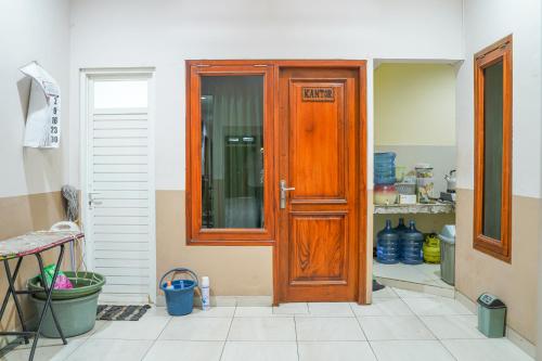 Una puerta de madera en una cocina con suelo de baldosa. en Singgahsini Jemursari en Djetak