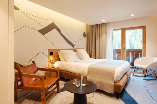a bedroom with a bed and a chair and a table at Best Western Chalet les Saytels in Le Grand-Bornand