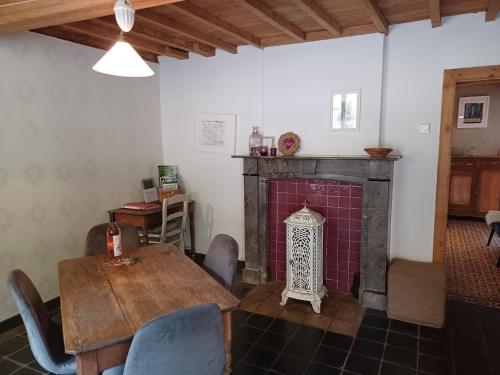 een woonkamer met een open haard en een tafel en stoelen bij La Ferme du Couchant in Beauraing