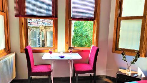 a table with two pink chairs and two windows at Sweet Home Kadıköy in Istanbul