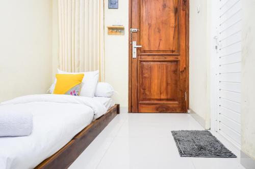 1 dormitorio con 1 cama y puerta de madera en Singgahsini Jemursari en Djetak