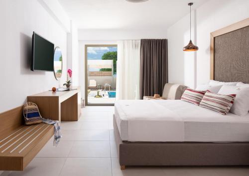 Schlafzimmer mit einem Bett, einem Schreibtisch und einem TV in der Unterkunft Imagine Luxury Suites in Nikiti