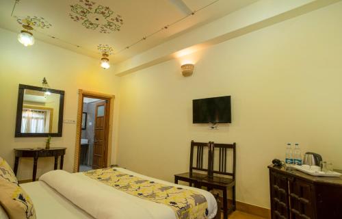 a bedroom with two beds and a tv on the wall at Tripli Hotels Prithvi Palace in Jaisalmer