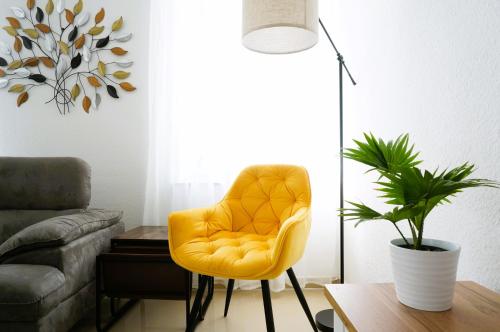 a yellow chair in a living room with a plant at Mein Apartment Flowers mit Kamin, bis 10 Personen in Frankenthal