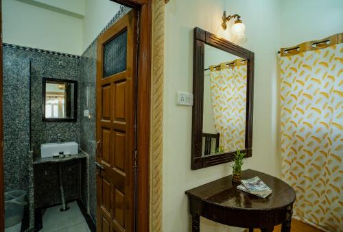 a bathroom with a sink and a mirror and a wooden door at Tripli Hotels Prithvi Palace in Jaisalmer