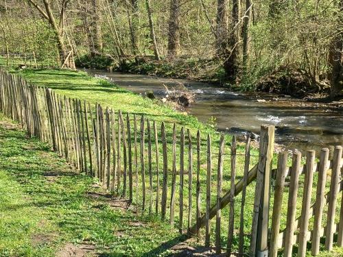 a wooden fence next to a river next to a field at La Ferme du Couchant in Beauraing