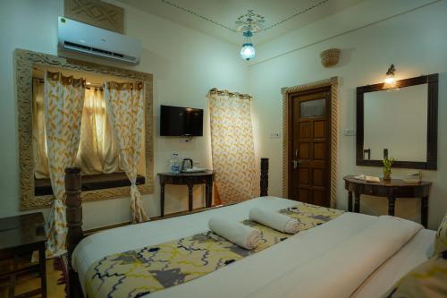 a bedroom with a bed and a table and a window at Tripli Hotels Prithvi Palace in Jaisalmer
