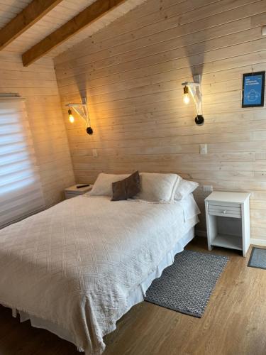 1 dormitorio con 1 cama y pared de madera en Cabañas El Galo, en Panguipulli