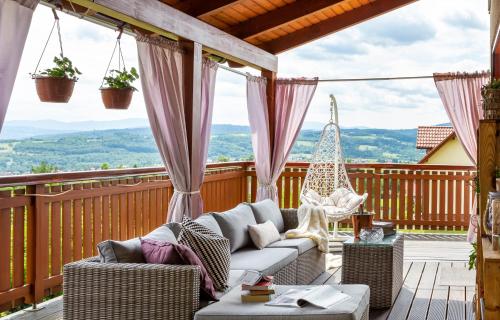 a patio with a couch and chairs on a deck at Dom z Widokiem Mucharz 405 in Mucharz