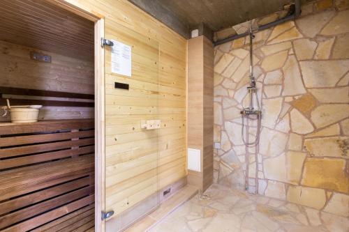 a shower in a bathroom with a stone wall at Dom z Widokiem Mucharz 405 in Mucharz