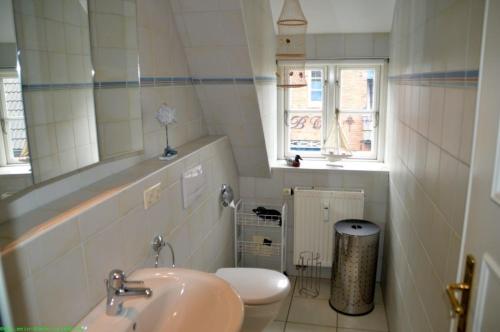 ein Badezimmer mit einem Waschbecken, einem WC und einem Spiegel in der Unterkunft Wohnen auf'm Lande HT 6 in Oldsum