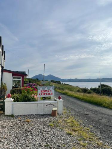 a sign on the side of a road next to a house at The Rowanberry Suite at Rowan Cottage in Elgol