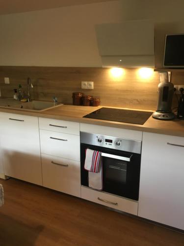 une cuisine avec des armoires blanches et un four à plaques de cuisson dans l'établissement L'instant present, à Caen