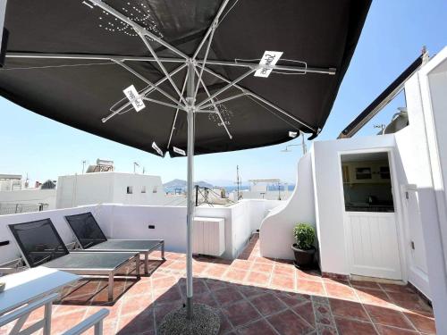 a patio with a black umbrella on a roof at Deluxe Ιδιωτικό δωμάτιο στην πόλη της Νάξου in Naxos Chora