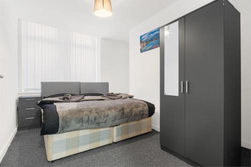a bedroom with a bed and a black cabinet at Bradford City Centre One and Two bedroom Apartments CONTRACTORS LONG STAY welcome Parking Available nearby paid in Bradford