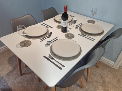 un tavolo bianco con piatti e bicchieri e una bottiglia di vino di Gorgeous 1 Bed Apartment in Wetwang a Great Driffield