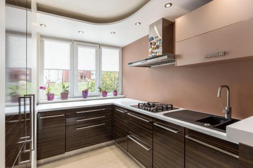 a kitchen with brown cabinets and a sink and windows at Jekabpils 2 Apartment in Rīga