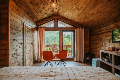 1 dormitorio con 1 cama, 2 sillas y ventana en Romantické ubytovanie pre dvoch v lese, en Banská Bystrica