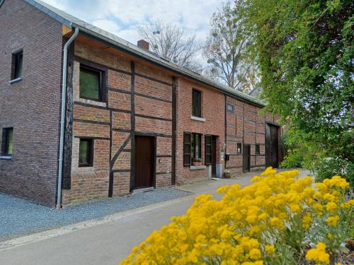 a brick building with yellow flowers in front of it at La Ferme du Couchant in Beauraing