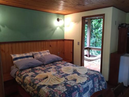 a bedroom with a bed with two towels on it at Pousada Sitio dos Pinhais in Visconde De Maua