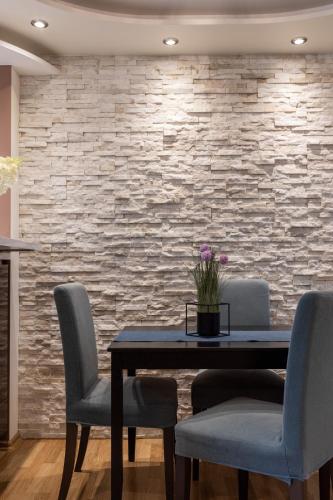 a dining room with a table and chairs and a stone wall at Jekabpils 2 Apartment in Rīga