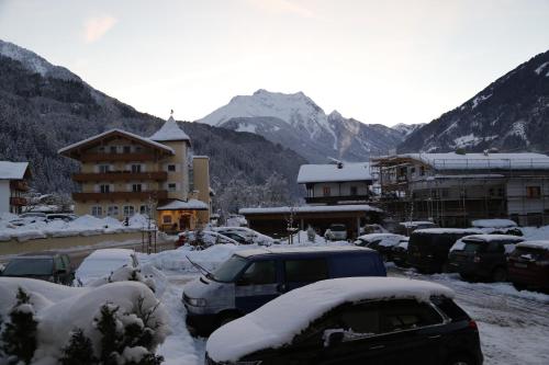 a parking lot covered in snow with buildings and cars at Hotel & Suites Glück Auf in Mayrhofen