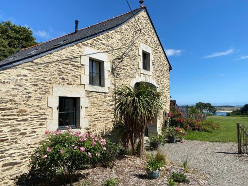une maison en pierre avec un palmier en face de celle-ci dans l'établissement Chambres d'Hôtes Bella Laïta, à Keranquernat