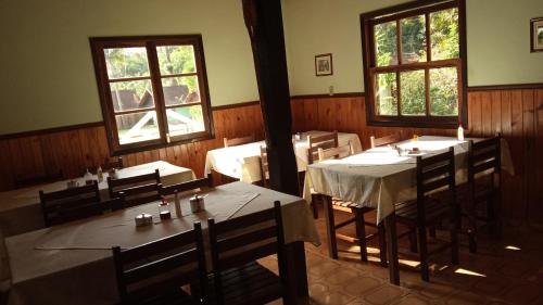 a dining room with tables and chairs and windows at Pousada Sitio dos Pinhais in Visconde De Maua