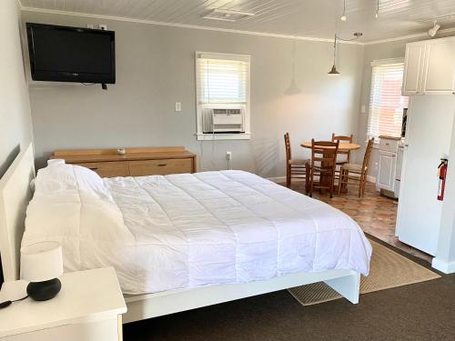 a bedroom with a large white bed and a kitchen at Tower Circle Motel in Buxton