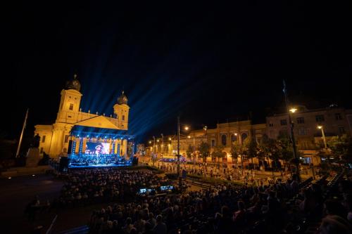 a crowd of people in front of a building at night at Visit Debrecen Apartman in Debrecen