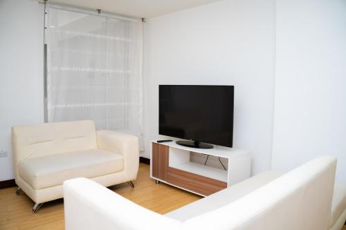 a living room with a television and a white couch at HotelSuizaApartamentos in Ipiales