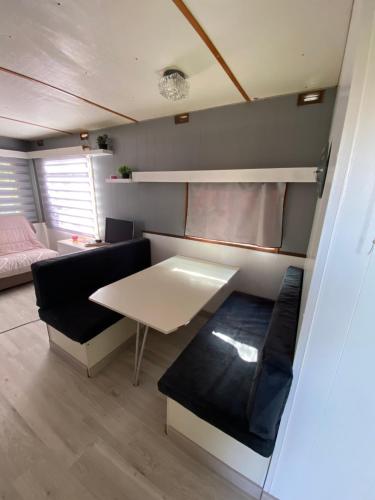 una pequeña sala de estar con mesa y sofá en Bungalow confortable proche de la mer en Linguizzetta