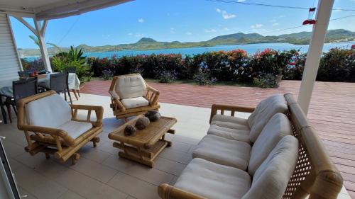 a living room with a couch and chairs and a view of the ocean at VILLA INDEPENDANTE MAGNIFIQUE VUE MER DES CARAIBES in Le Marin
