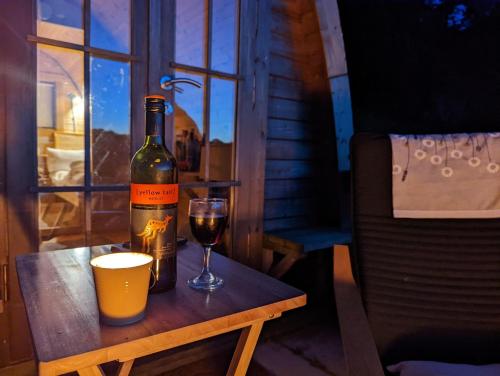 una bottiglia di vino e un bicchiere su un tavolo di Cosy Pod-Cabin near beautiful landscape in Omagh a Omagh