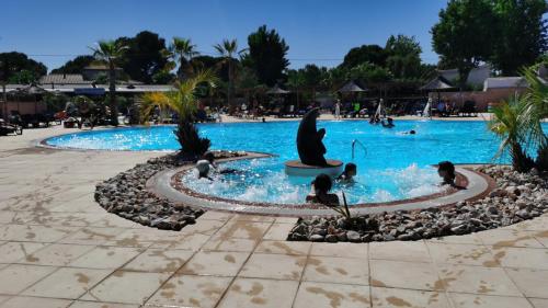 a pool at a resort with people in the water at Les sables du midi in Valras-Plage