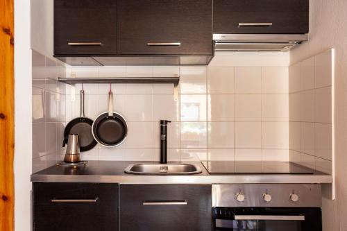 - une cuisine avec des placards noirs et un évier dans l'établissement Suite Via Torino, à Milan