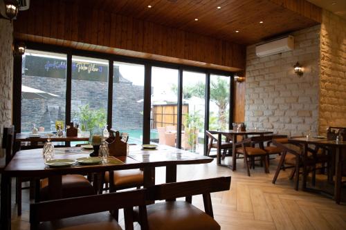 a restaurant with wooden tables and chairs and windows at Palm Villas in Amritsar