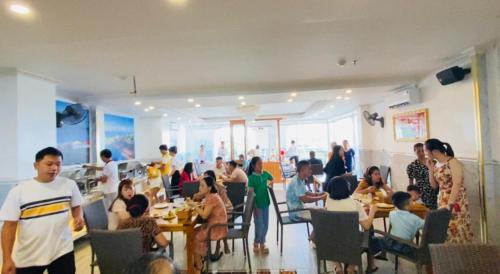 a group of people sitting at tables in a restaurant at Rockmila Hotel in Phu Quoc