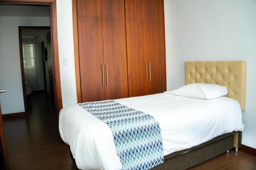 a bedroom with a bed and a wooden cabinet at HotelSuizaApartamentos in Ipiales