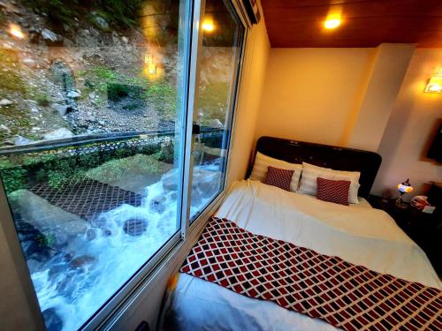 a small room with a window with a bed and a window at Blue Water Resort Kalam in Kārandūkai