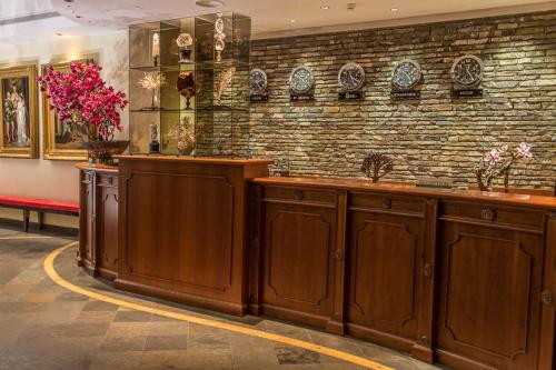 a kitchen with wooden cabinets and a brick wall at Lux Garden Hotel in Azuga