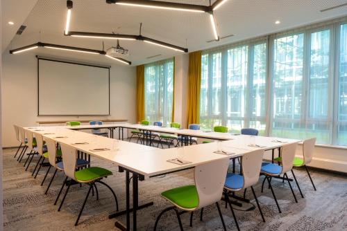 a conference room with tables and chairs and a whiteboard at Flightgate Munich Airport Hotel, a member of Radisson Individuals in Hallbergmoos