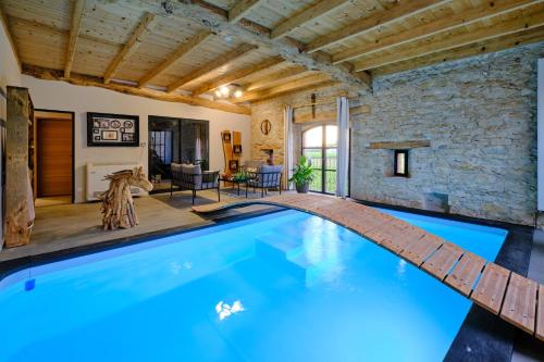 a large swimming pool in a house with a stone wall at Séjour LUXE pour couple avec PISCINE INTÉRIEURE terrasse SPA privé Green de GOLF in Alzonne