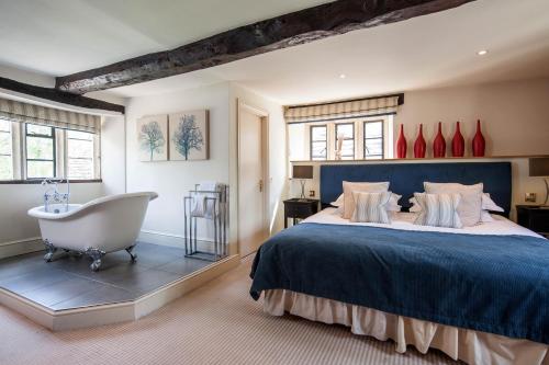 a bedroom with a large bed and a bath tub at The Slaughters Country Inn in Lower Slaughter