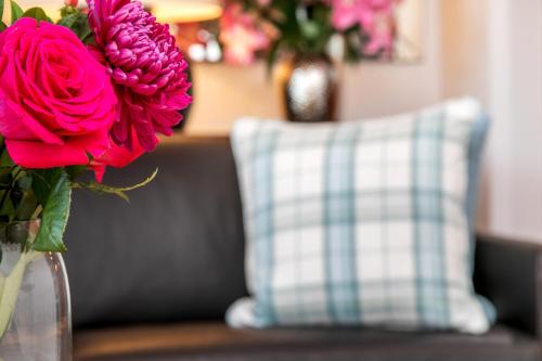 a vase filled with pink flowers next to a pillow at The Sky Penthouse in Winchester