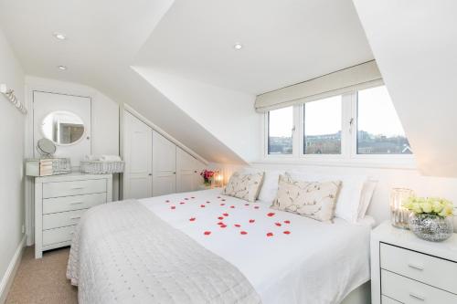 a white bedroom with a white bed with red roses on it at The Sky Penthouse in Winchester