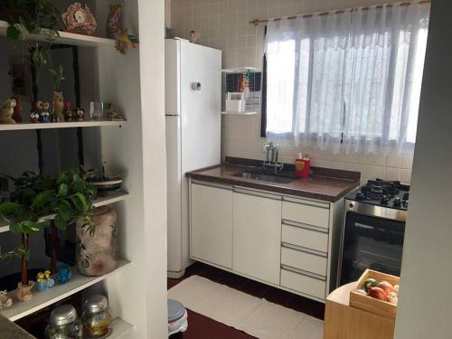 una cucina con frigorifero bianco e lavandino di Apartamento aconchegante perto da praia a Caraguatatuba