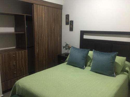 マサトランにあるDepartamento Mareta Mazatlánのベッドルーム1室(緑のシーツと青い枕が備わるベッド1台付)